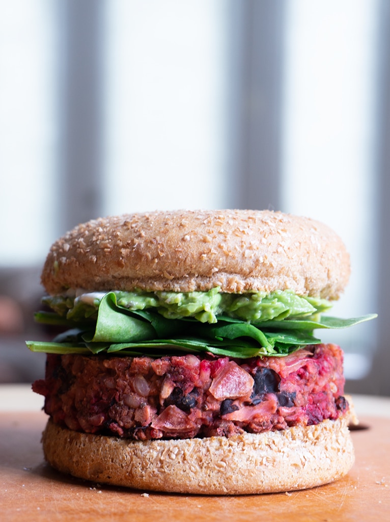 Black bean beet burger on a bun with spinach and avocado