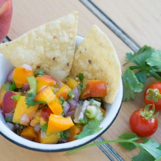 Little white bowl with black trim filled with peach salsa
