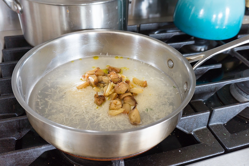 roasted garlic on stovetop with cheese and water