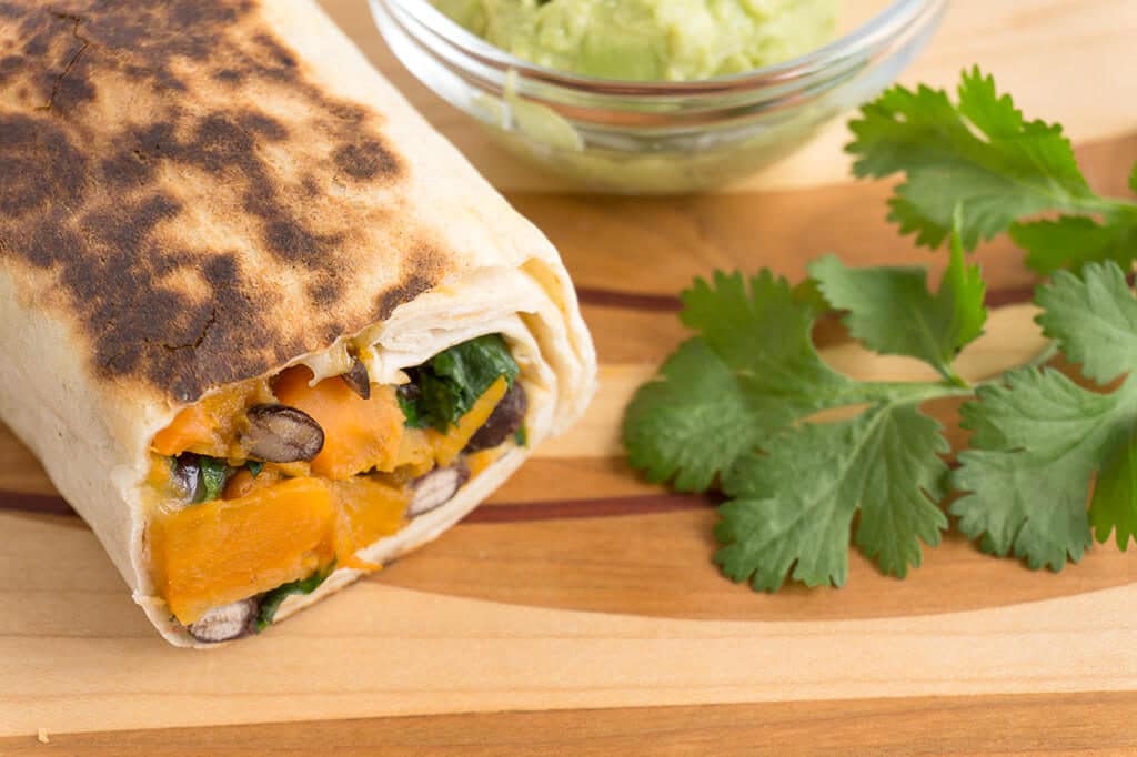 burrito with avocado sauce and cilantro