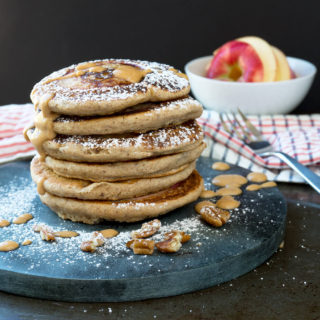 stack of pancakes with apple in background