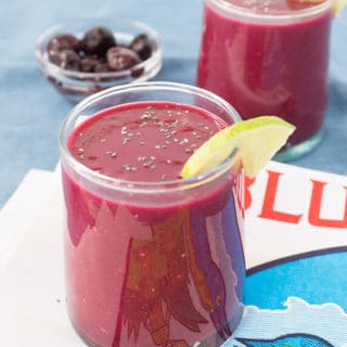 beet smoothie in a glass with a lime wedge