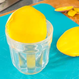 using a glass to peel a mango