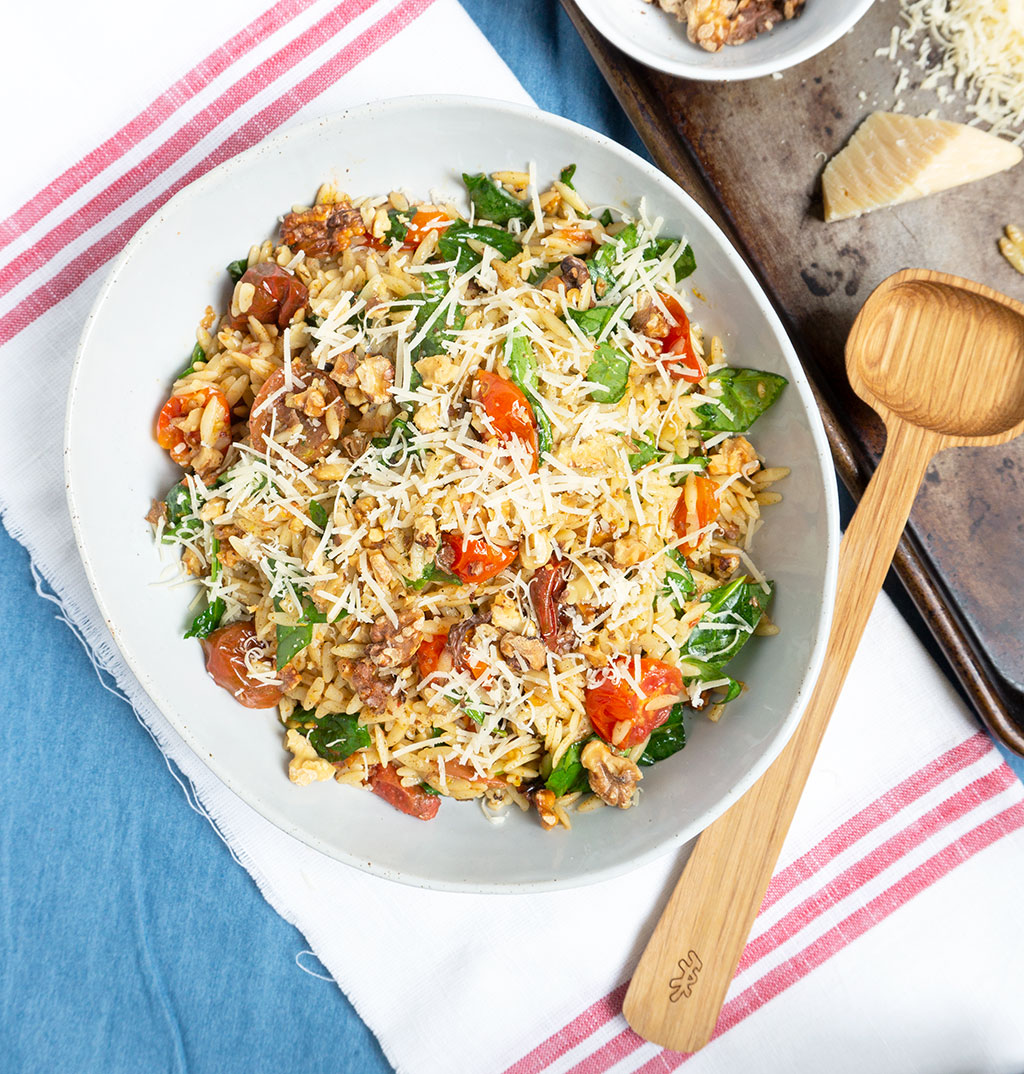 Spicy Roasted Tomato Pasta Salad is the most delicious way to use cherry tomatoes - especially if they're homegrown! Orzo pasta tossed with sweet roasted tomatoes, fresh spinach, toasted walnuts then seasoned with lemon and harissa to create a spicy and sweet pasta salad with a nutty crunch. | #PASTA | #SALAD | #TOMATOES | #VEGETARIAN | #Recipes at OatandSesame.com