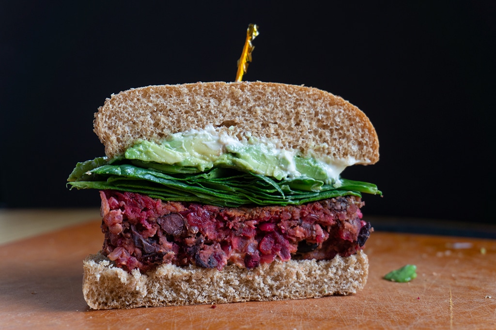Red Beet Burger on bun sliced in half with toothpick on top