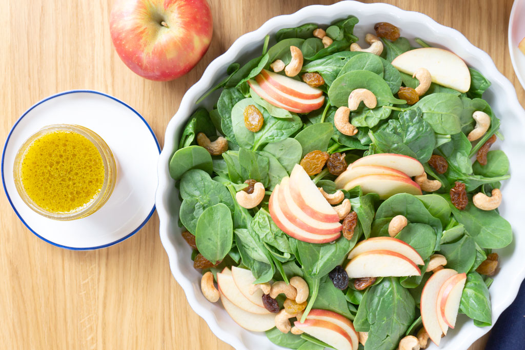 A BRIGHT AND CRISP APPLE SALAD! Packed with spinach, this Apple-Cashew Spinach Salad is dressed with a tangy apple cider vinaigrette and mixed with creamy cashews and sweet apple and raisins. | #AppleRecipes | #AppleSalad | #SaladIdeas | #VegetarianRecipes | #HealthyRecipes at OatandSesame.com #oatandsesame