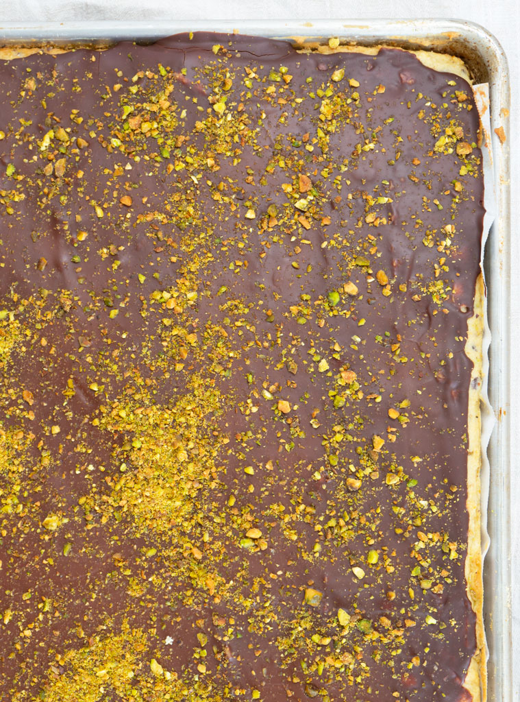 chocolate ganache spread all over cannoli cake with crushed pistachios