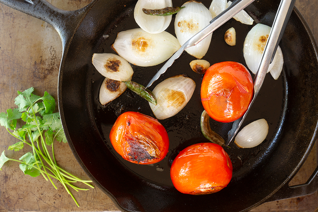 cast iron skillet with browned tomatoes, onion, garlic and peppers